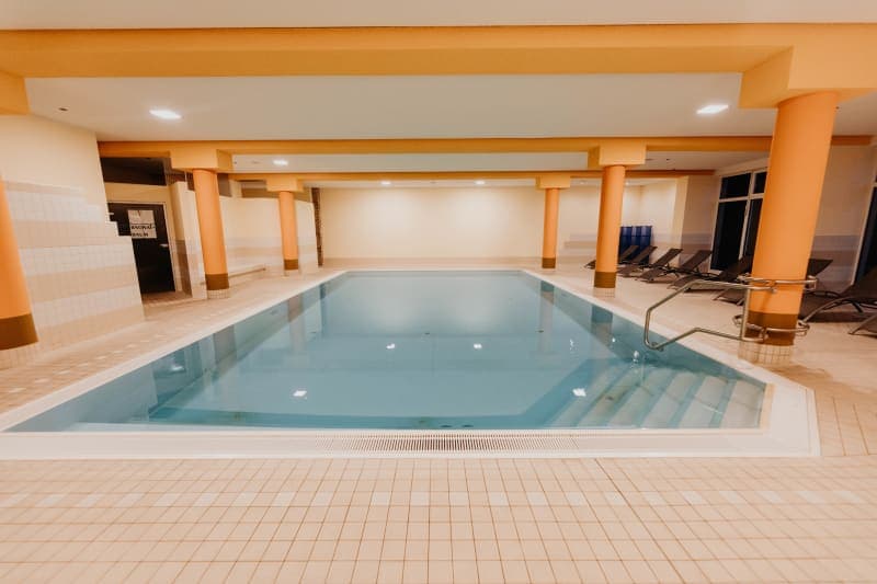Indoor pool with terracotta columns, clear water and loungers in a warm ambience