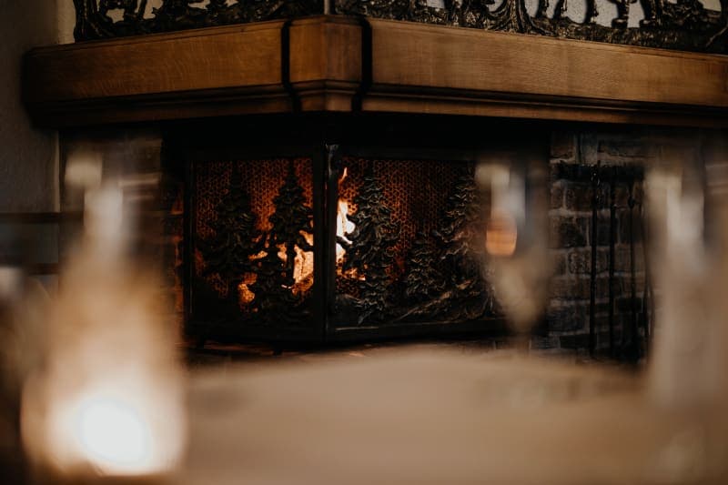 Crackling fireplace with an artful forest-design metal screen in a rustic event room