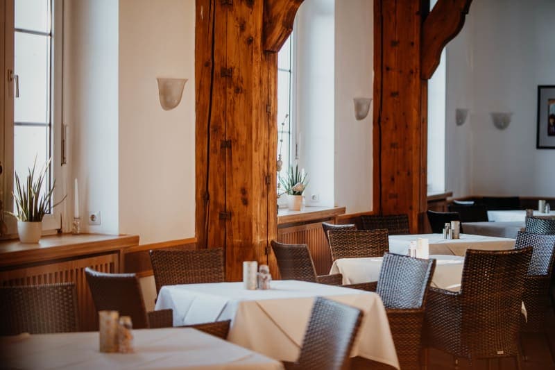 Event room with rustic wooden beams, set tables and woven chairs